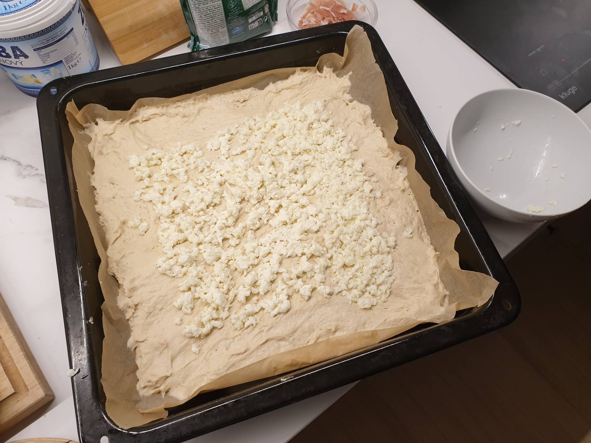 Roztažené těsto a vrstva strouhané mozzarelly